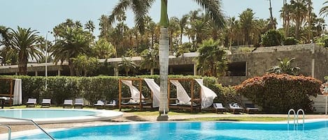 A swimming pool with lounge chairs and palm trees.