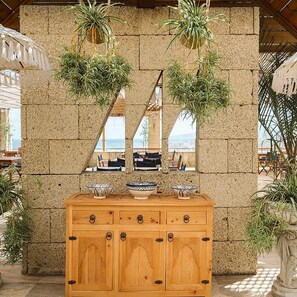 A wooden cabinet with decorative handles, a stone wall, and potted plants. - Precise Resort Tenerife (Los Realejos)