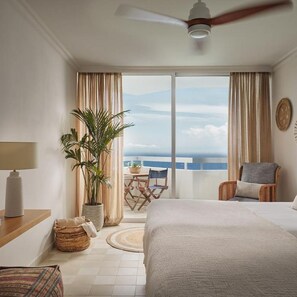 A hotel room with a bed, a ceiling fan, a potted plant, a view of the ocean, and a balcony with chairs. - Precise Resort Tenerife (Los Realejos)