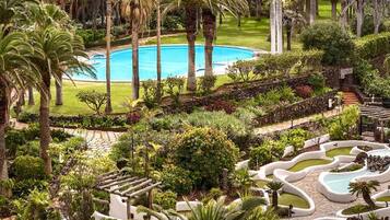 Un resort con piscina central, rodeado de palmeras y jardines cuidados.