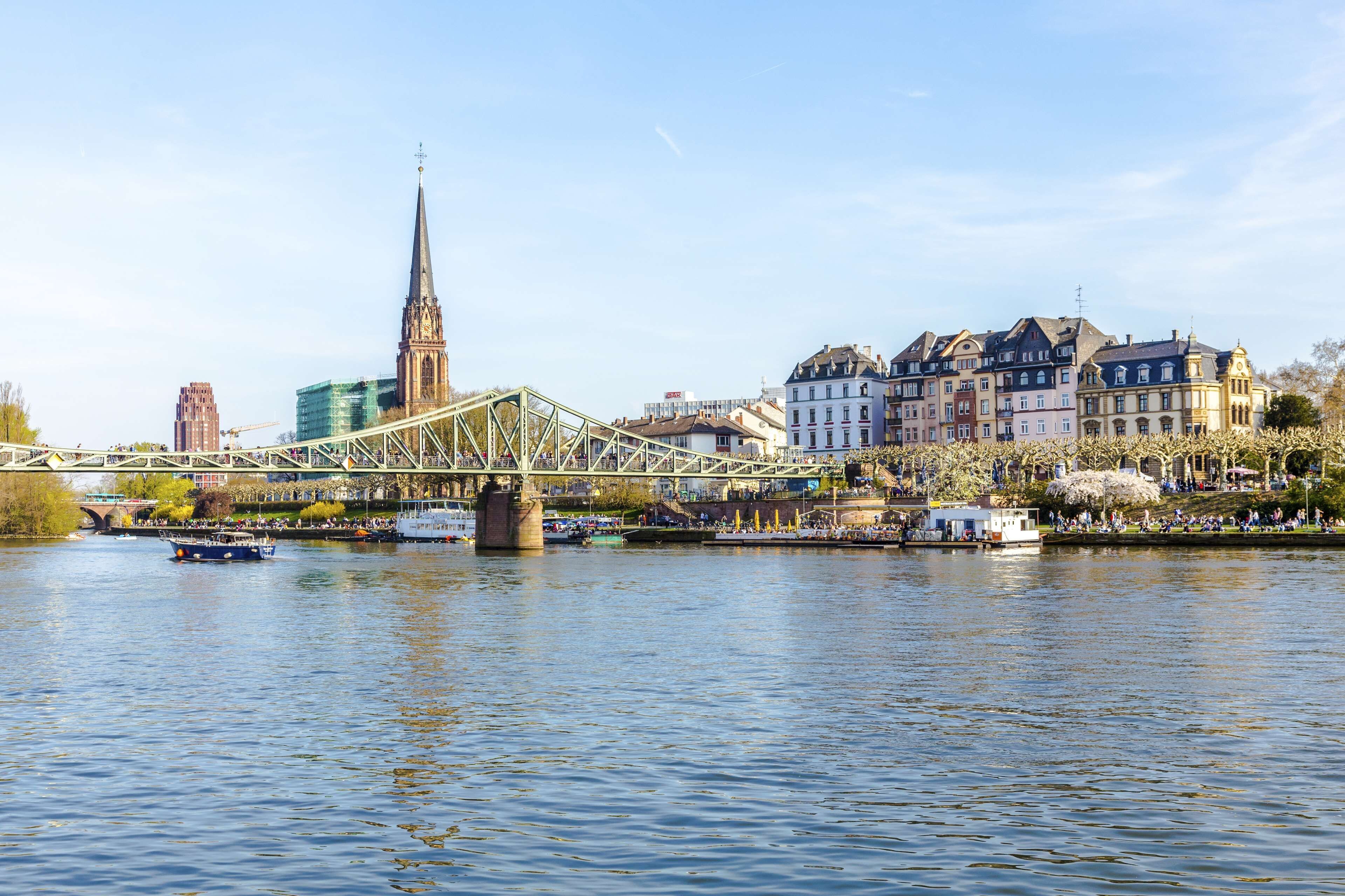 A river with a bridge, historic buildings, and a church spire.
