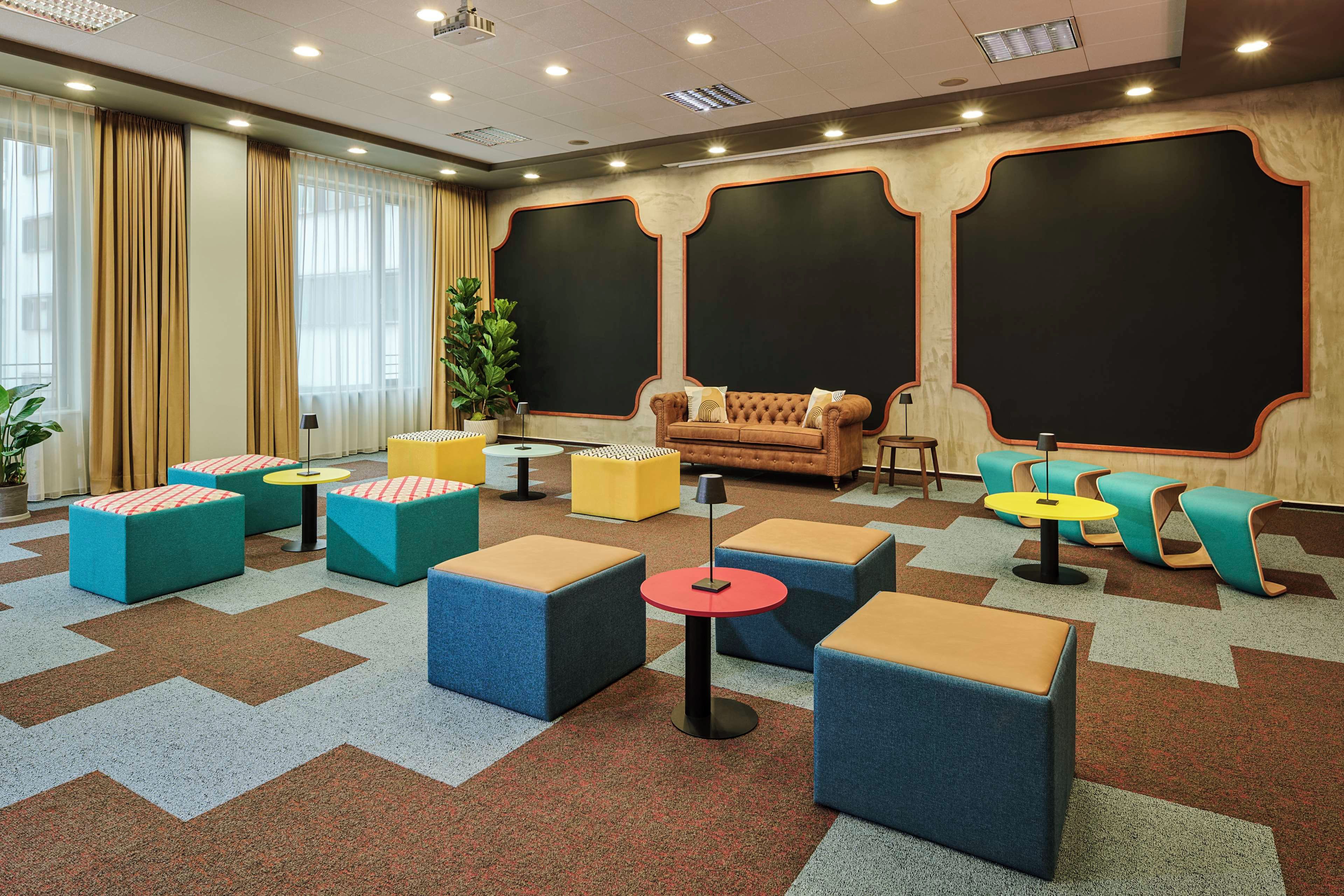 A modern lounge area with a sofa, multiple seating options, and a large plant.