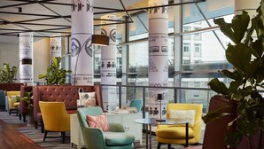 Un espace de détente moderne avec des fauteuils colorés, un canapé capitonné et de grandes fenêtres donnant sur la ville.