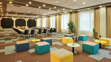 Une salle de conférence avec une longue table, des chaises et des poufs colorés.