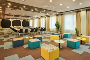 Una sala de conferencias con una larga mesa, sillas y otomanas coloridas.