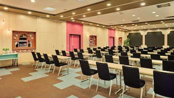 A conference room with rows of tables and chairs, a projector, and a large screen.