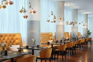 Un comedor moderno con una mesa larga, varias sillas y lámparas colgantes.