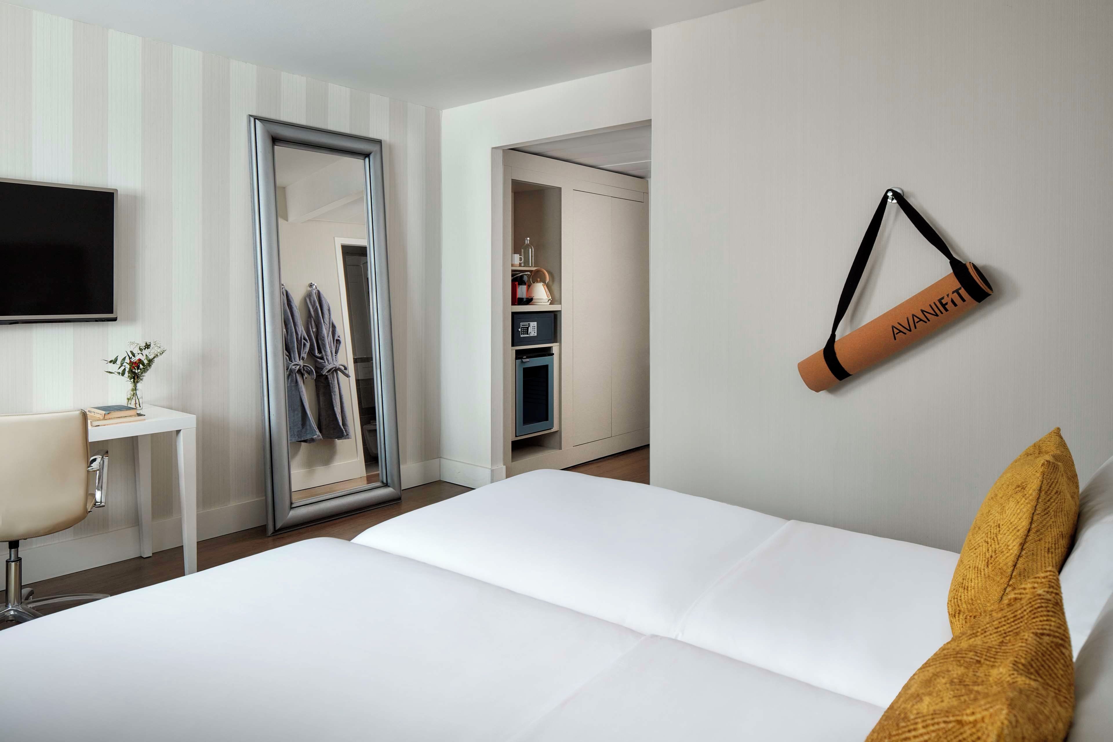 Een hotelkamer met een bed, bureau, televisie, kledingkast en een badkamer.