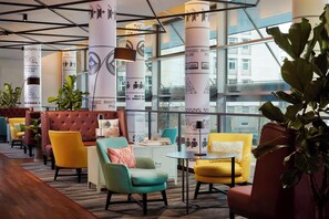A modern lounge area with leather sofas, a coffee table, and potted plants.