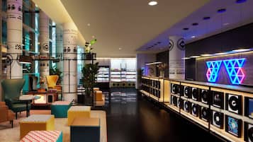 A modern lounge area with seating, a record wall, and a view of the cityscape.