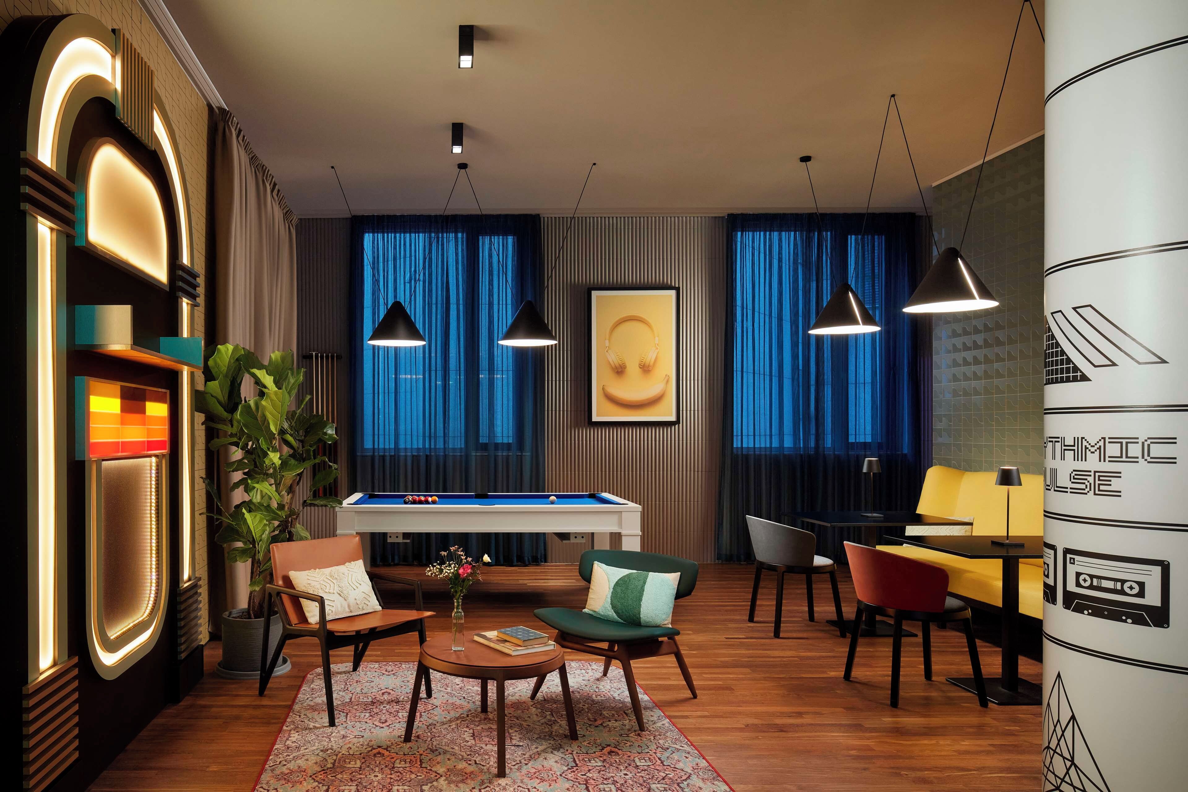 A modern lounge area with a pool table, comfortable seating, and ambient lighting.