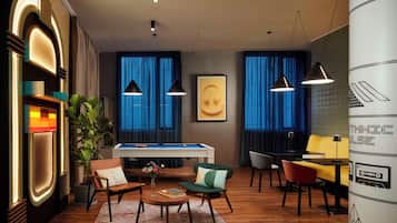 A modern lounge area with a pool table, comfortable seating, and ambient lighting.