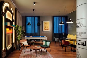 Un área de estar moderna con mesa de billar, asientos cómodos e iluminación ambiental.