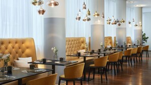 Un espace de restauration moderne avec une longue table, de nombreuses chaises et des luminaires suspendus.