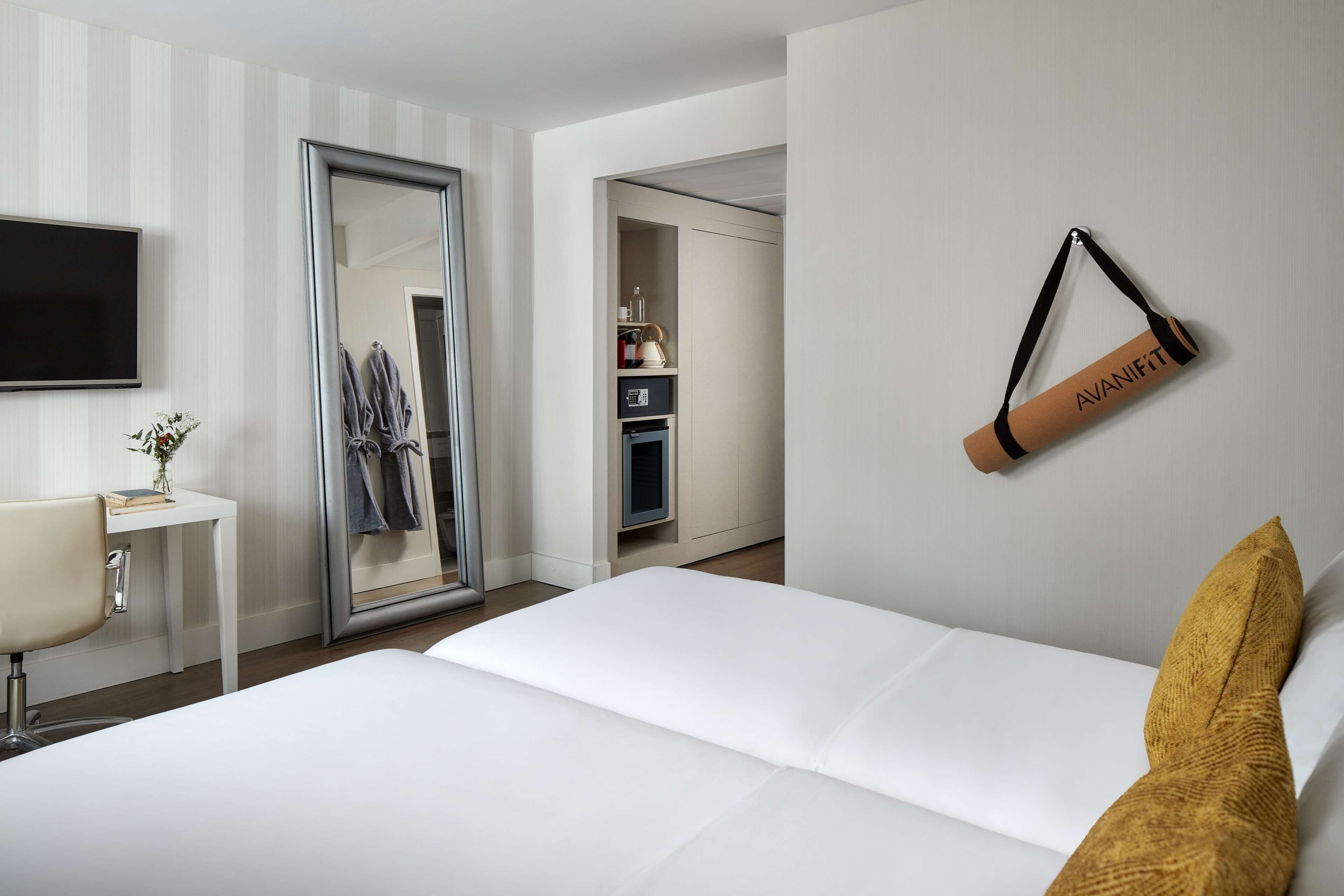 A hotel room with a bed, a desk, a TV, a wardrobe, and a mirror.
