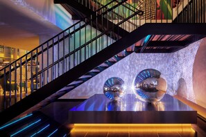 Un escalier moderne avec une rampe en verre, menant à un niveau inférieur.