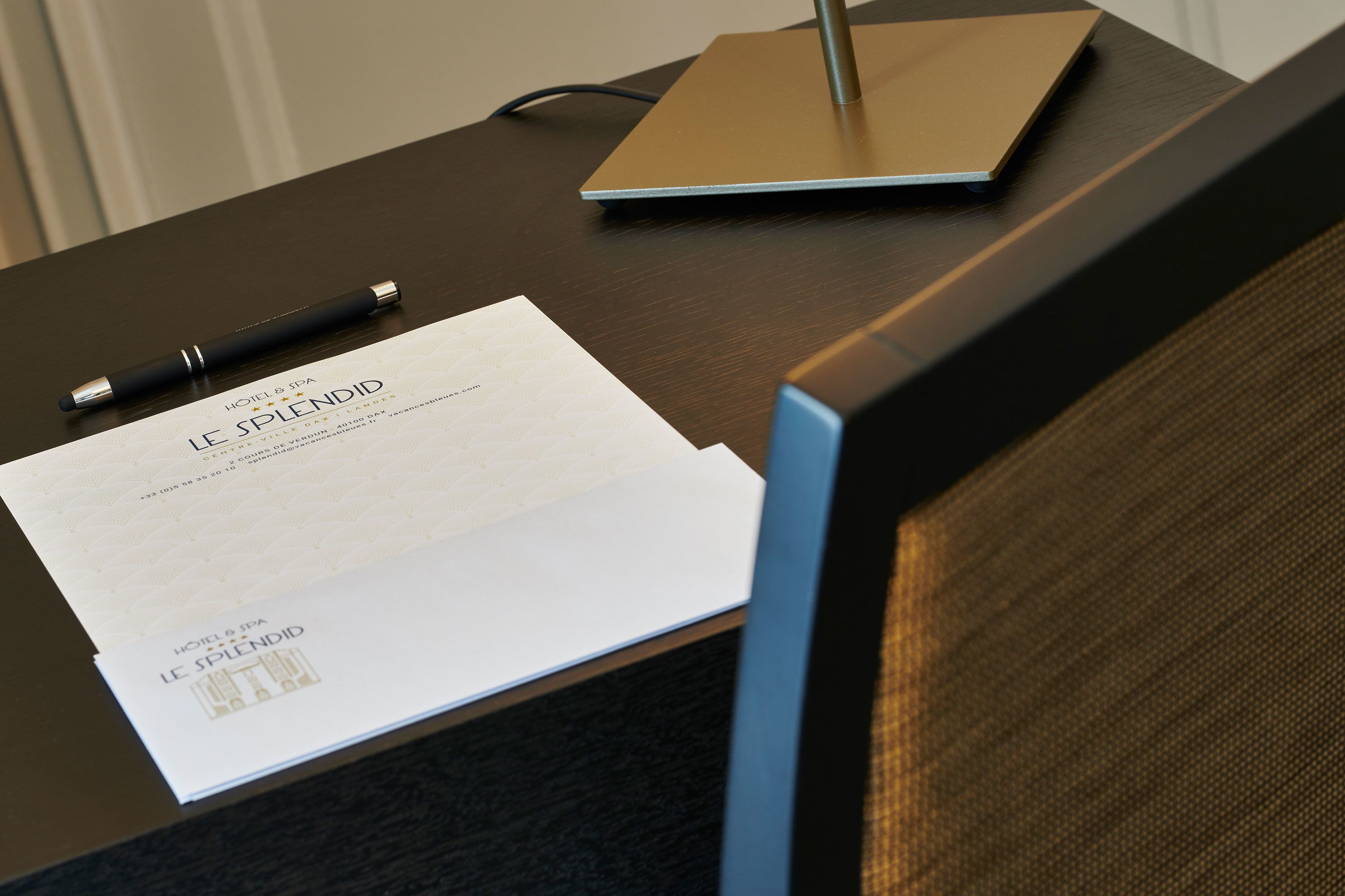 A hotel desk with a laptop, a pen, and a document titled "HOTEL & SPA LE SPLENDID".
