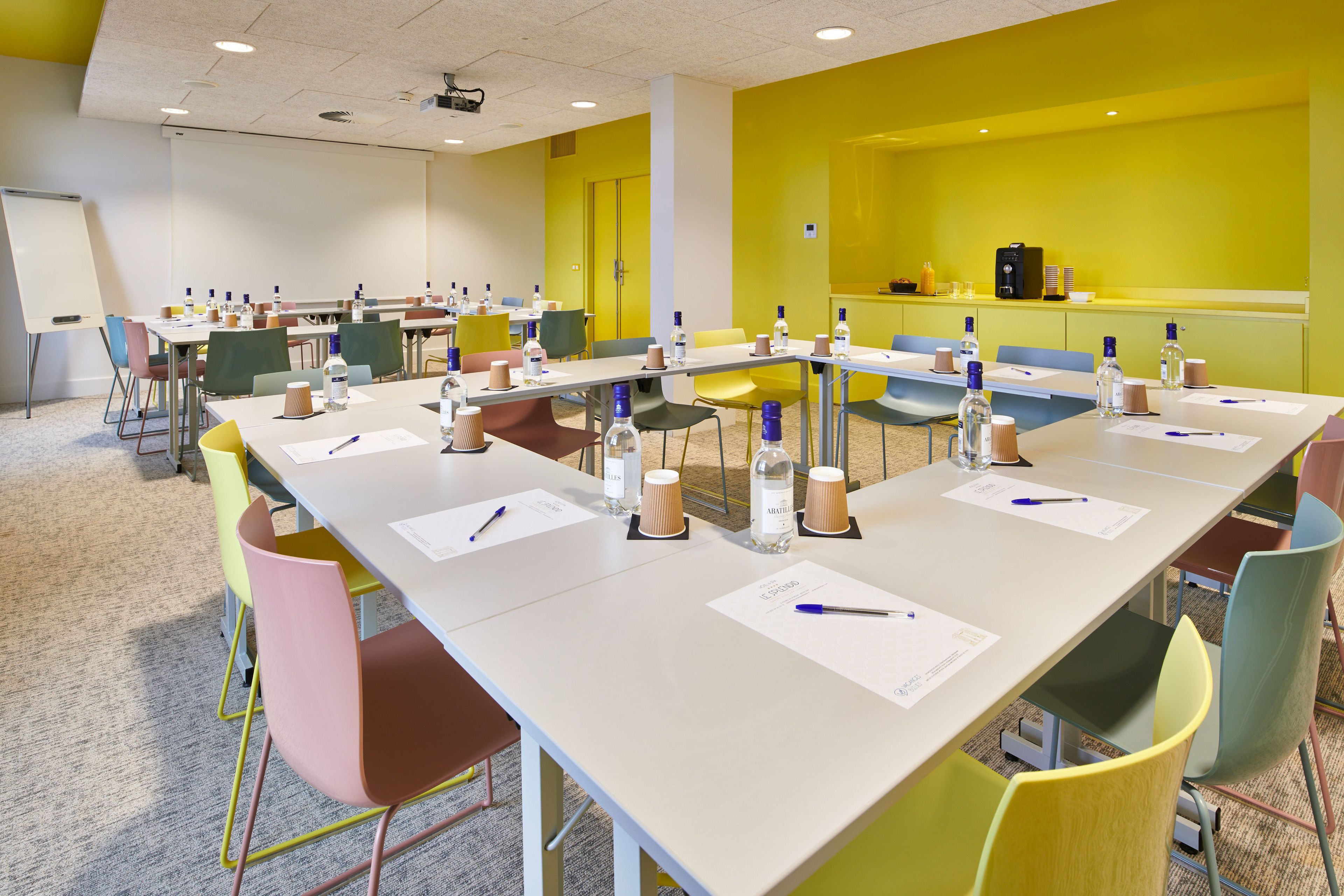 A conference room with multiple tables, chairs, and a whiteboard.