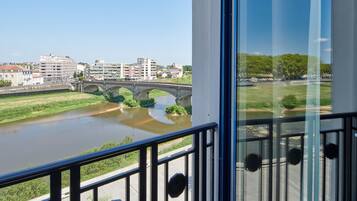 Un balcón con vista a un río, un puente y edificios al fondo.