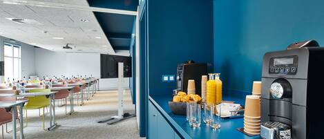 Un área de desayuno moderna con una máquina de café, dispensadores de jugo y un mostrador tipo buffet.