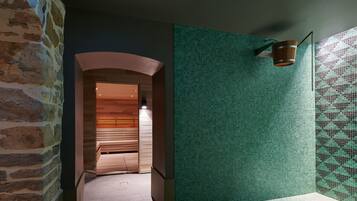 A spa area with a wooden bench, a tiled wall, and a hanging bucket.