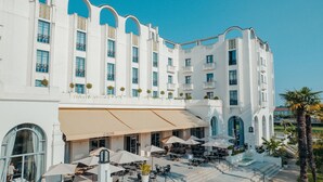 Un bâtiment blanc doté de balcons, d’une terrasse et d’un espace café.