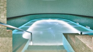 Un bain à remous avec un revêtement intérieur en carrelage et une rambarde en métal.
