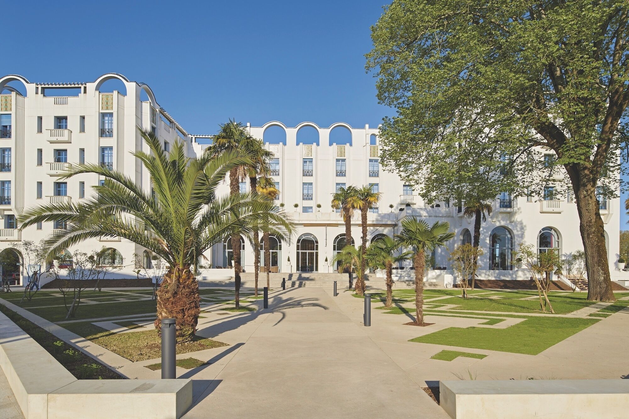 Un edificio con ventanas de arco y un patio central con palmeras.