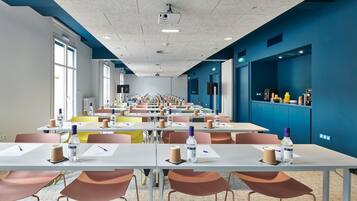 A conference room with multiple tables, chairs, and a projector on the ceiling.