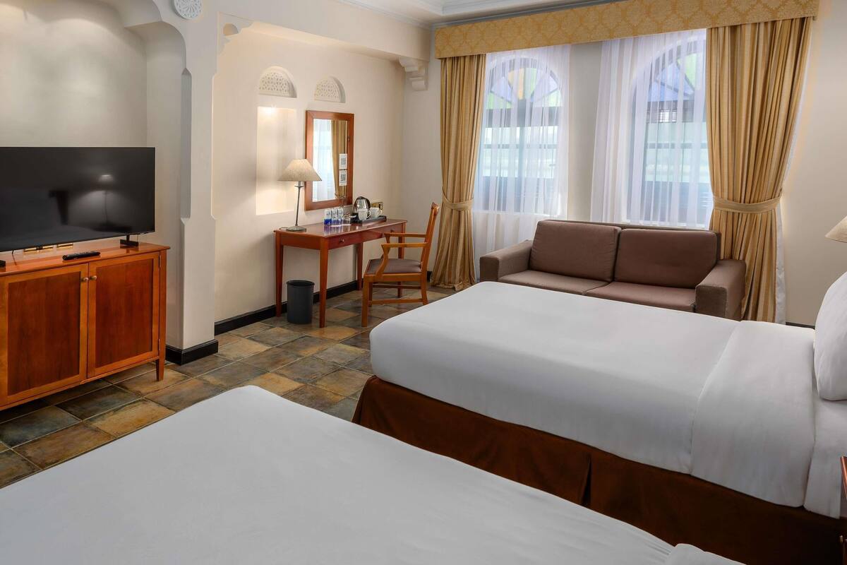 A hotel room with a bed, a desk, a television, and a sofa.