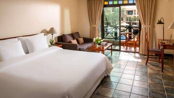 Habitación de hotel con una cama grande, un sofá, una mesa de centro, un escritorio y vistas al exterior.