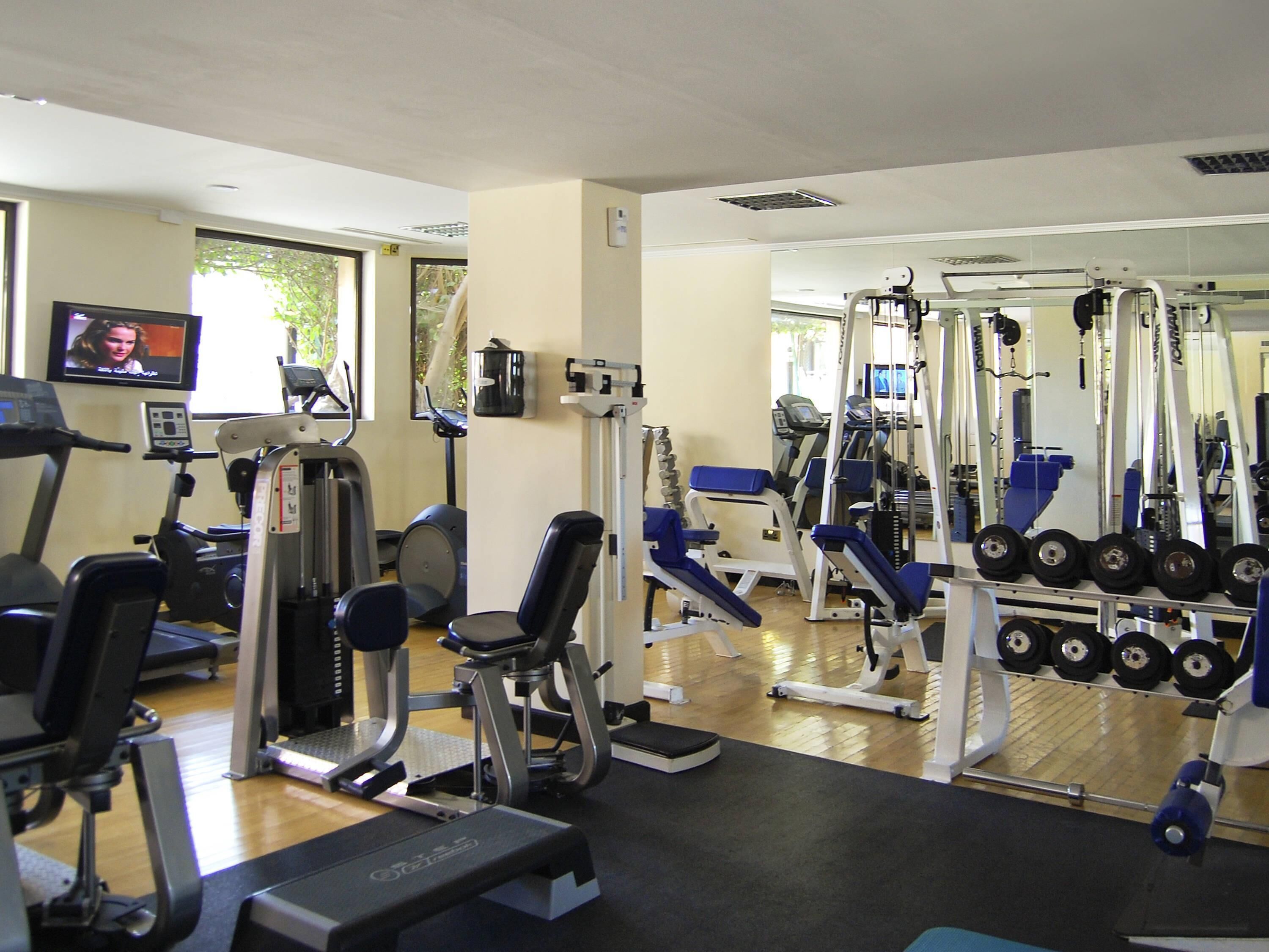 A gym with exercise equipment, a television, and a window.
