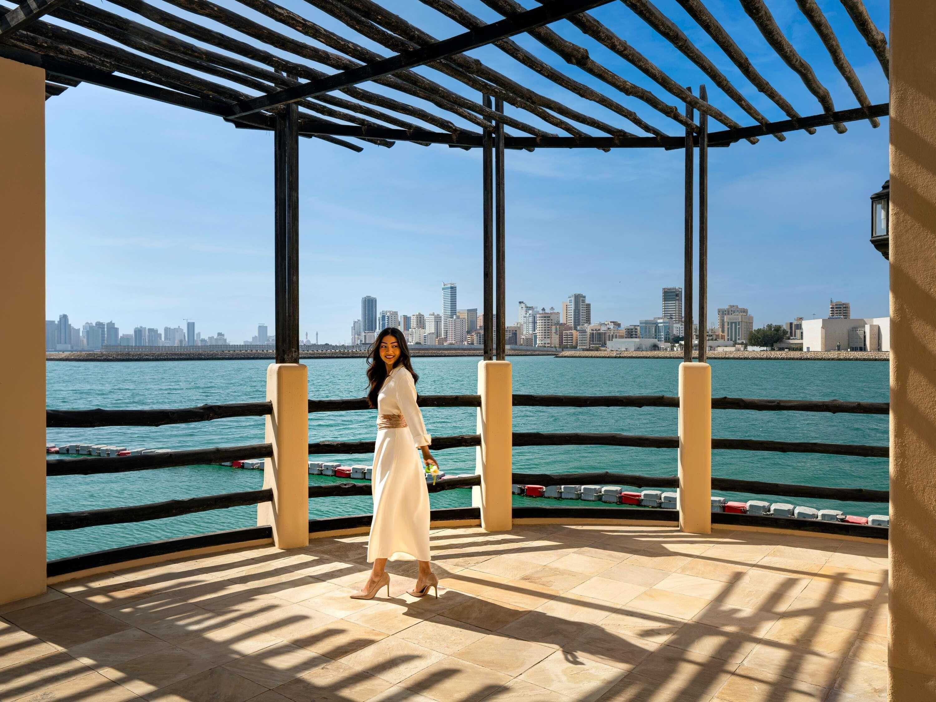 A person standing on a tiled balcony with a city skyline in the background.