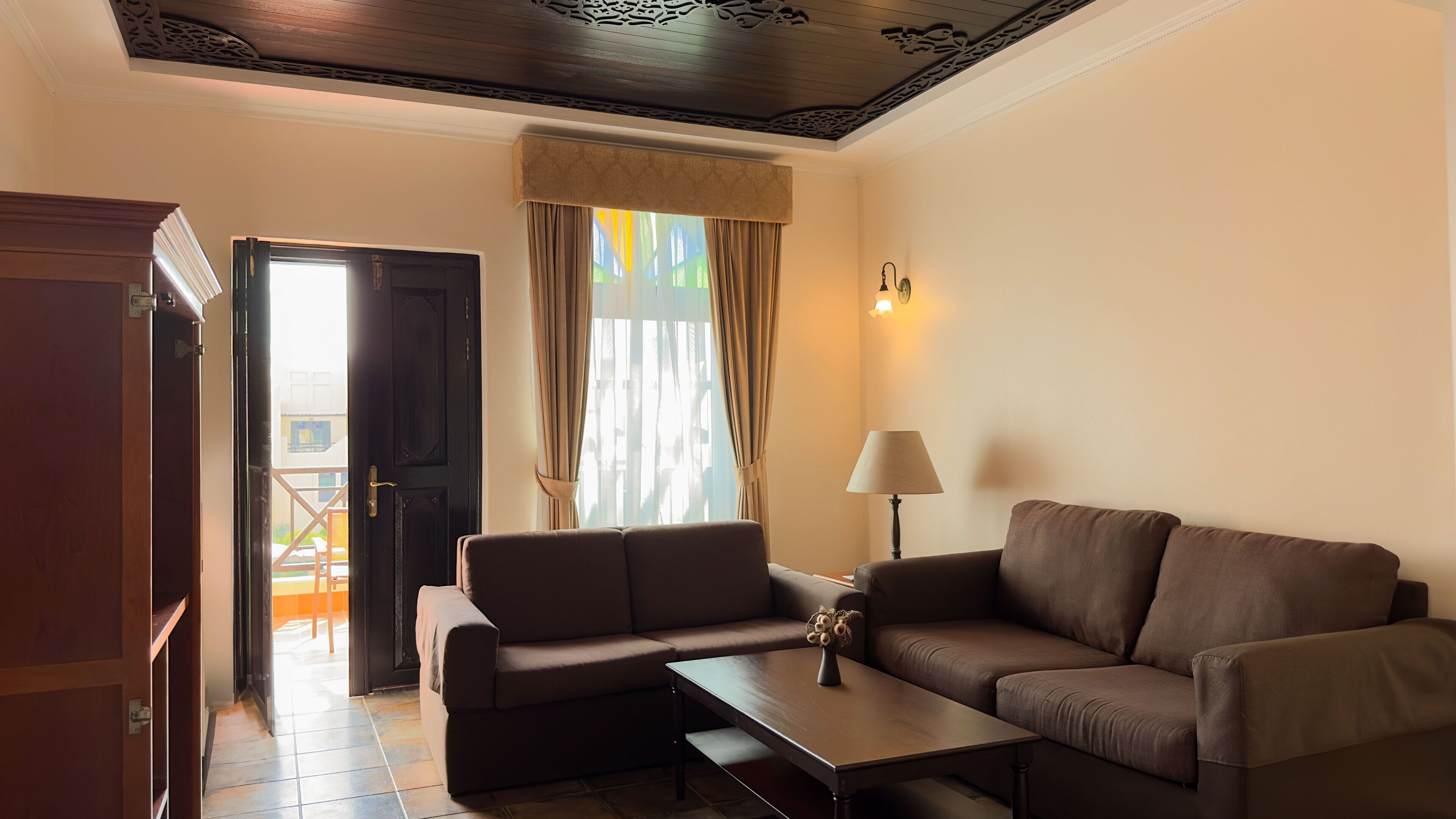 Una sala de estar con un sofá, una mesa de centro, una lámpara y una puerta que da a un espacio exterior.