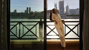 A person leaning on a balcony railing with a city skyline in the background. - Novotel Bahrain Al Dana Resort (Manama)