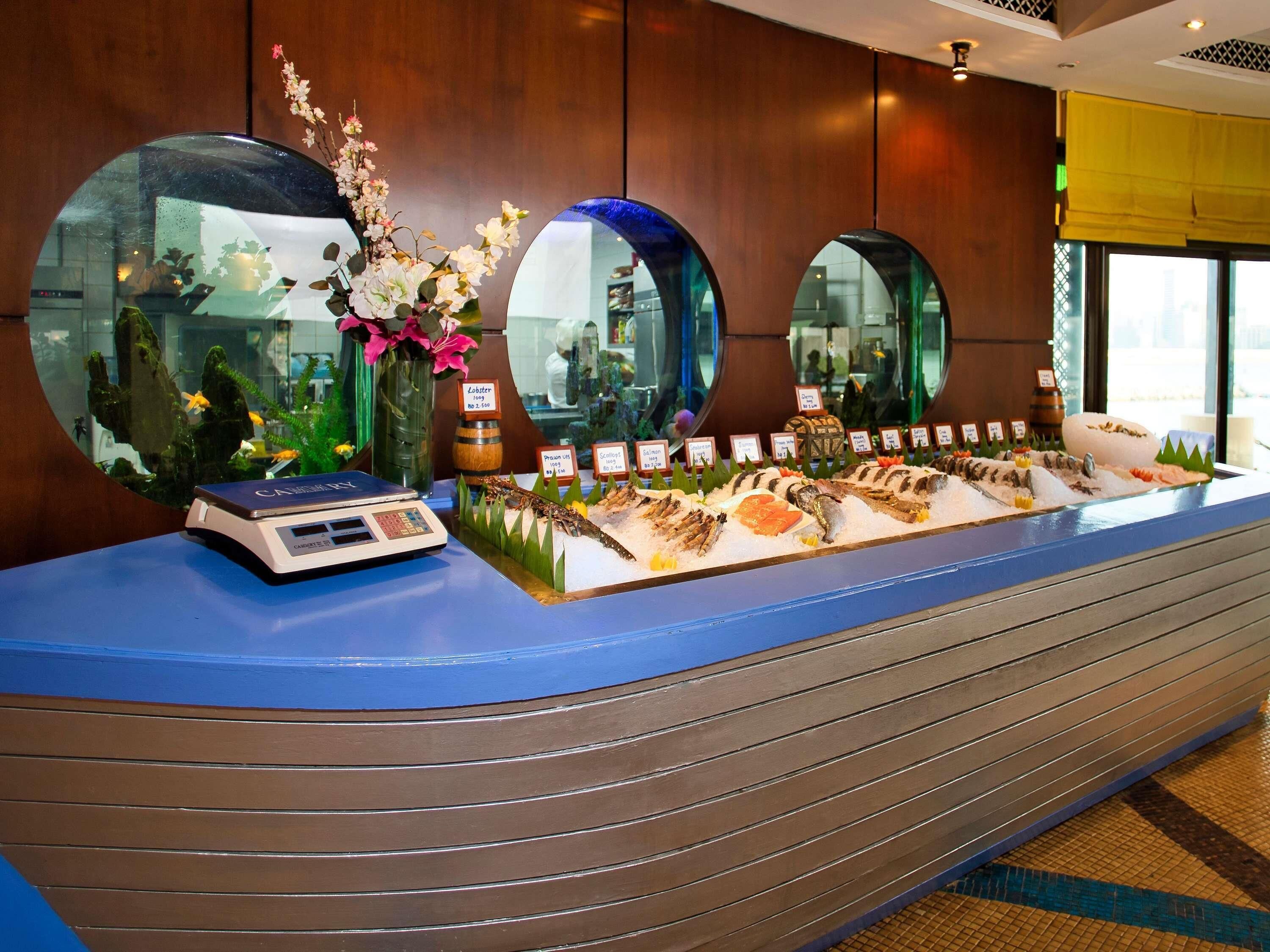 A seafood display with labels, a scale, and decorative plants.