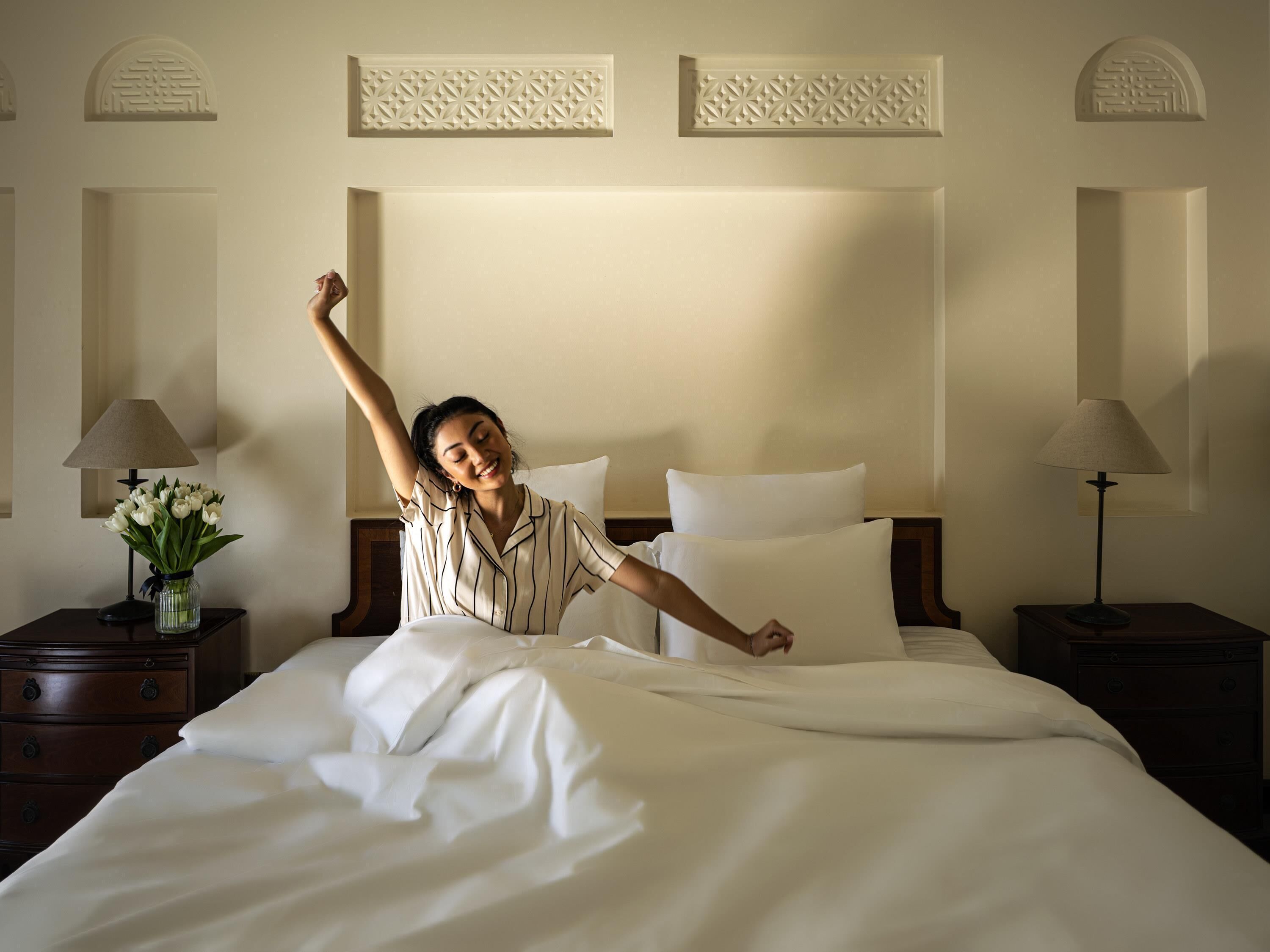 A hotel room with a large bed, two bedside tables, and a decorative wall panel.