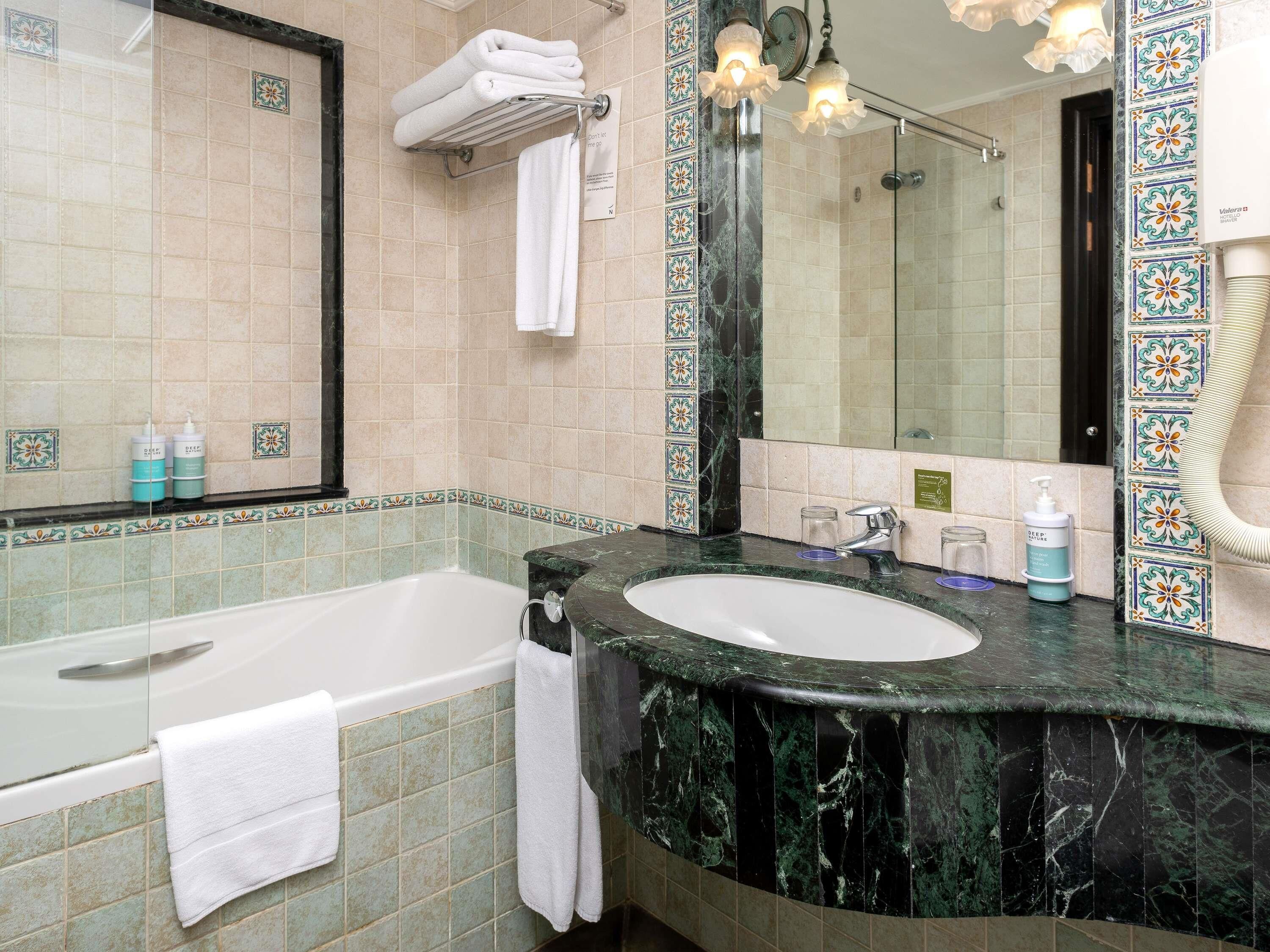 Een badkamer met een bad, wastafel, spiegel en douche.