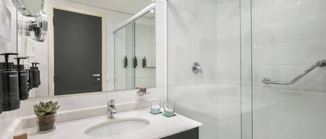A modern bathroom with a white sink, a large mirror, and a glass-enclosed shower area.