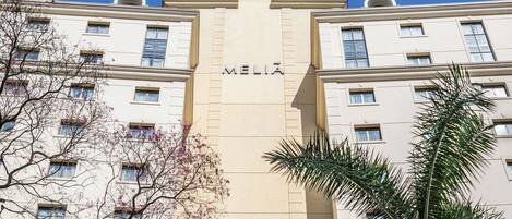Un immeuble à plusieurs étages dont la façade porte en grand le nom « MELIA ».