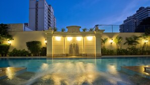 Una piscina con fuente, rodeada por un muro bajo con plantas e iluminación.
