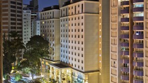 Un hotel de varios pisos con un diseño moderno, con balcones y una fachada bien iluminada.