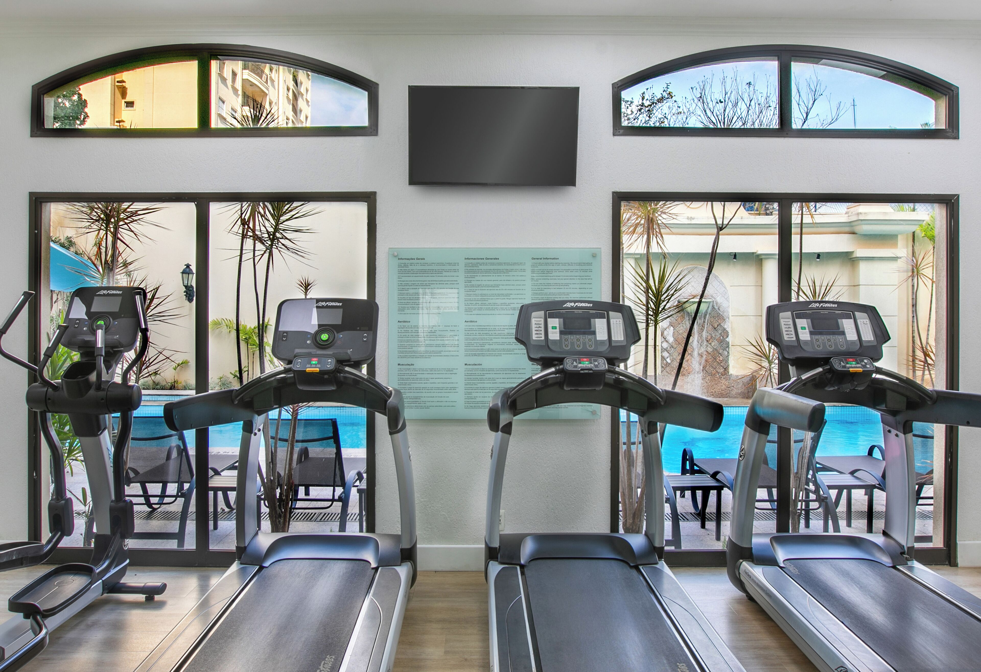 A fitness area with treadmills, a pool, and a view of the outdoors.