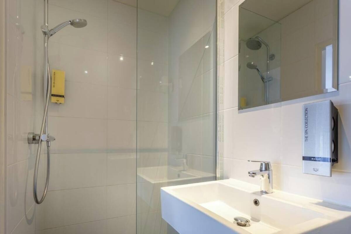 A modern bathroom with a glass shower enclosure, a white sink, and a mirror.