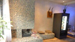 A cozy living area with a stone fireplace, comfortable seating, and a bookshelf. - Hotel Victorie (Amsterdam)