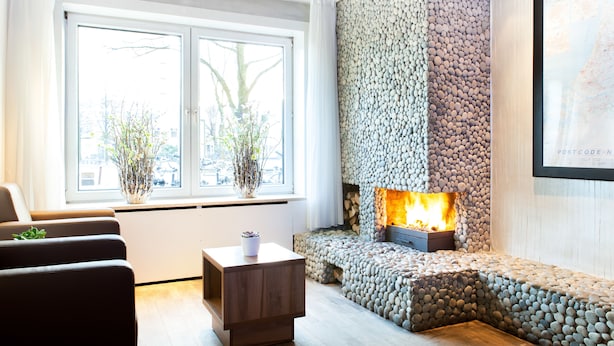A modern living room with a stone fireplace, a sofa set, and a coffee table. - Hotel Victorie (Amsterdam)