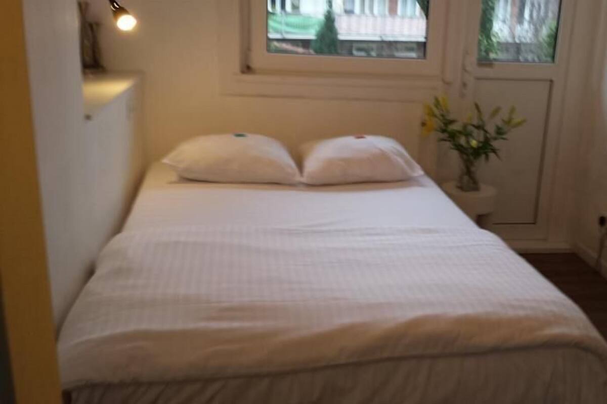 A small, neatly made bed with white bedding in a compact room.