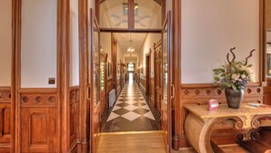 A hallway with a checkered floor, wooden doors, and a vase with flowers on a table. - Muthu Newton Hotel (Near Inverness Airport) (Nairn)