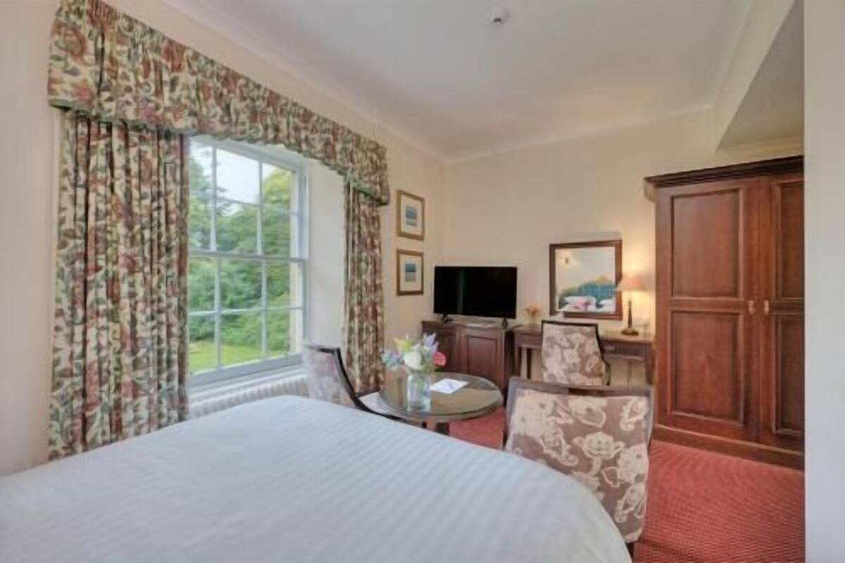 Una habitación de hotel con cama, televisión, escritorio y silla.