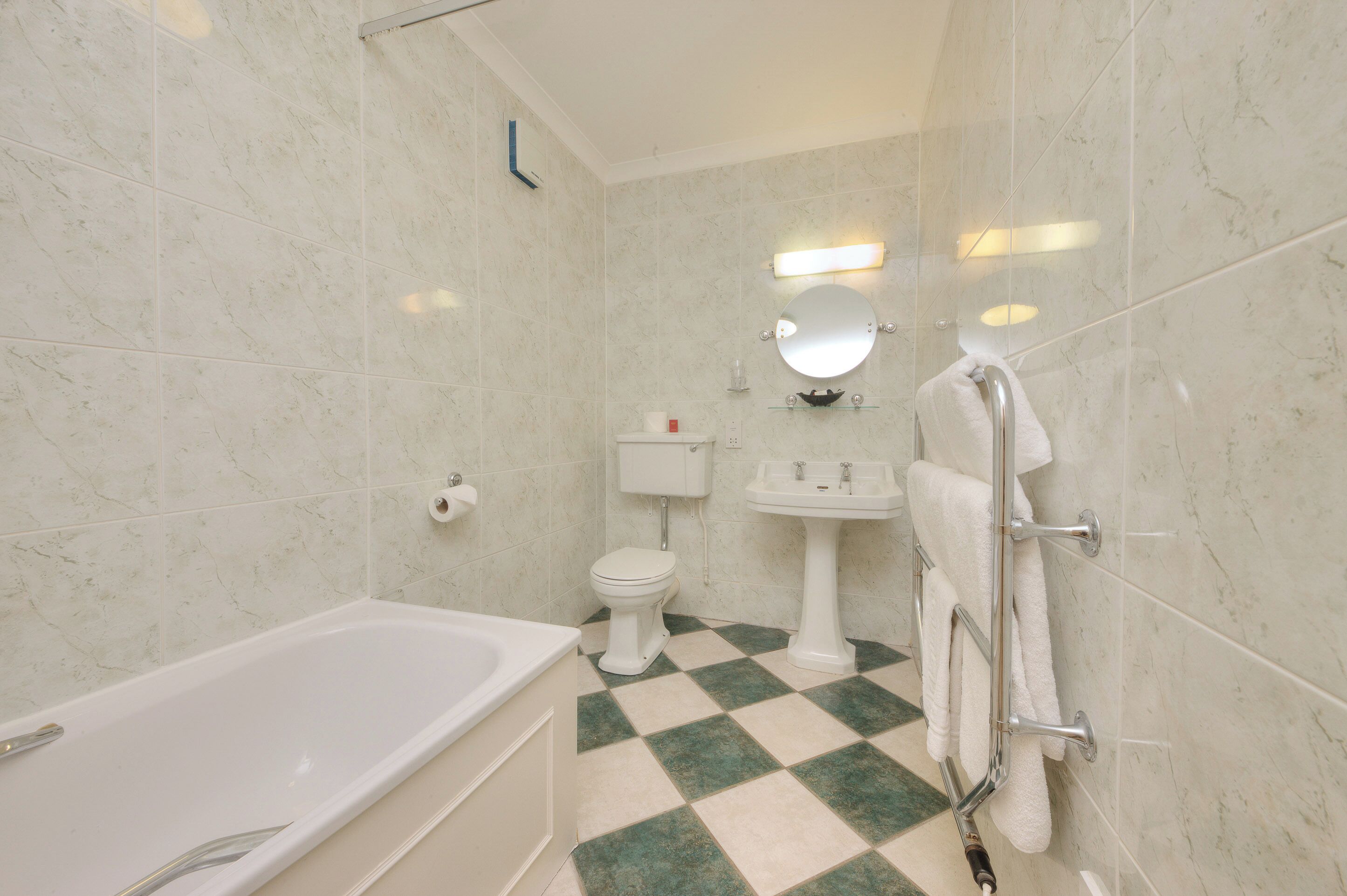 A bathroom with a white bathtub, a toilet, a sink, and a mirror.